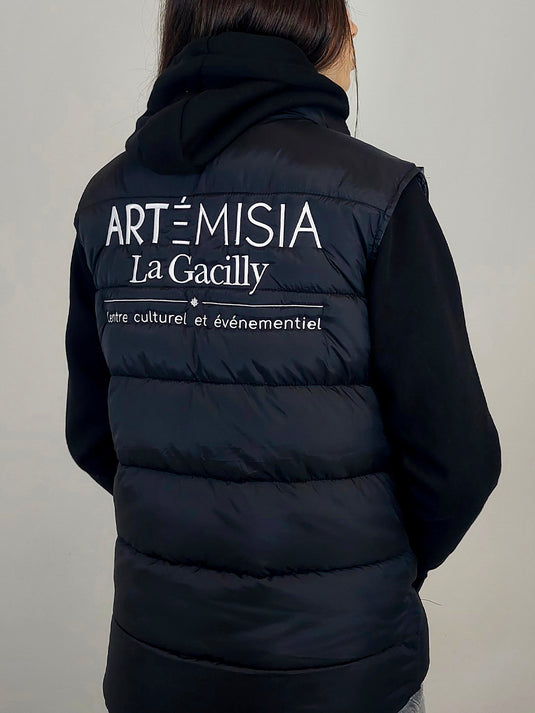 femme avec une doudoune sans manches brodée du logo de la salle de spectacle de La Gacilly
